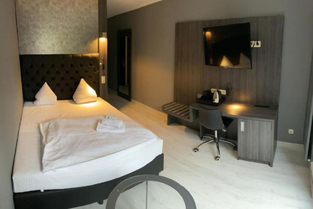 Hotelkamer met bureau, tv en koffiezetapparaat in SL'otel im Parforcehaus in Saksen-Anhalt in Duitsland.