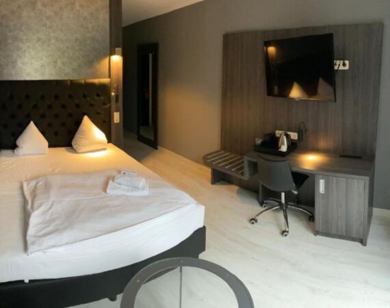 Hotelkamer met bureau, tv en koffiezetapparaat in SL'otel im Parforcehaus in Saksen-Anhalt in Duitsland.