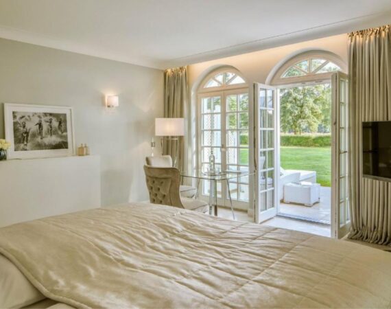 Kamer met een tweepersoonsbed, een televisie en deuren naar het terras Villa Contessa in Duitsland.