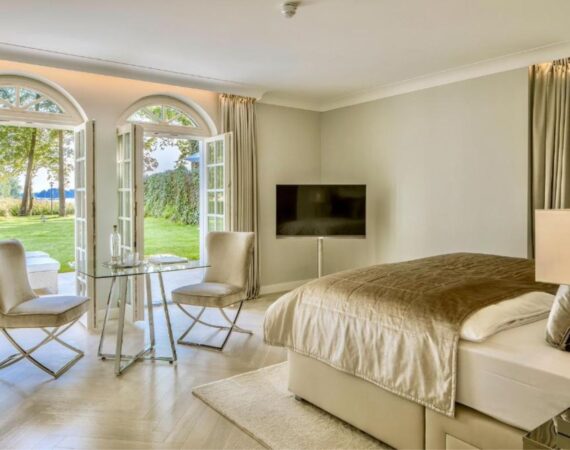 Kamer met een tweepersoonsbed, een televisie en deuren naar het terras Villa Contessa in Duitsland.