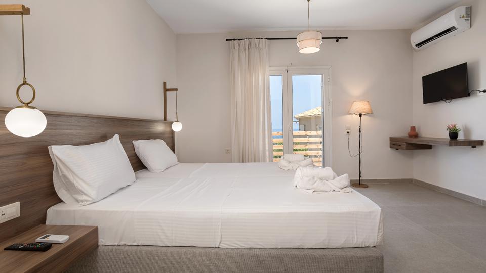 Kerri Villas in Griekenland slaapkamer met een tweepersoonsbed, airconditioning en een televisie.