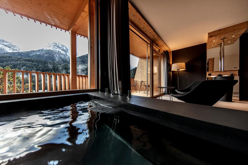 Hotelkamer met een jacuzzi en een balkon met uitzicht op de bergen Hotel Arnica Scuol in Graubünden Zwitserland.