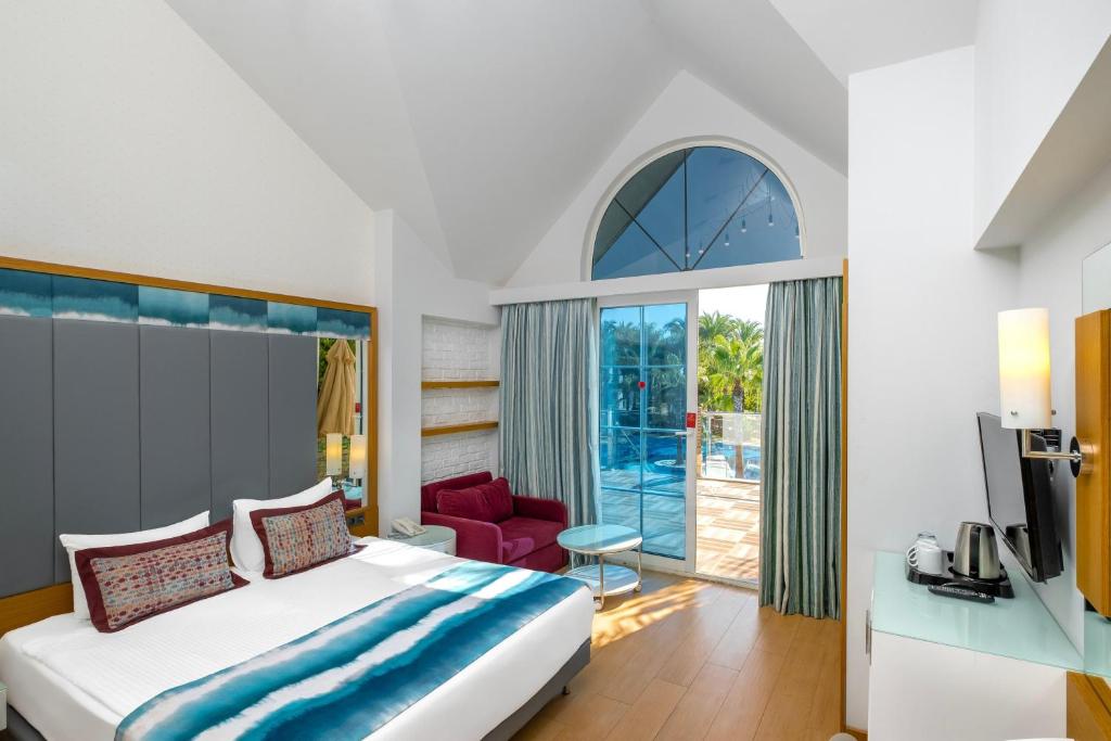 Suite villa met een tweepersoonsbed en een televisie Long Beach Alanya in Turkije.