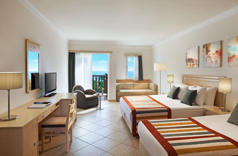 Kamer met twee tweepersoonsbedden, een televisie en een balkon met uitzicht op zee Paloma Grida in Turkije.